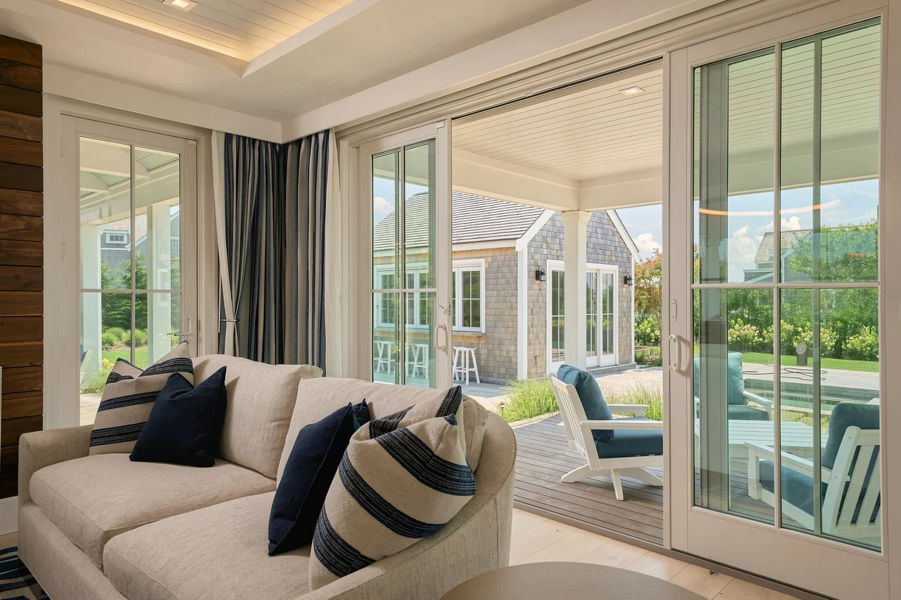 Coastal living room with white seating and folding glass doors opening to the pool terrace